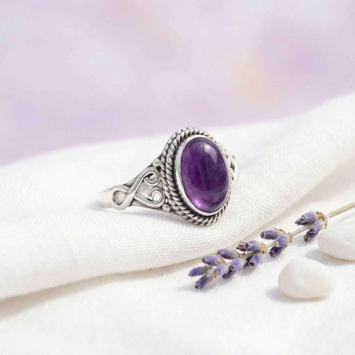 Silberring mit Amethyst auf hellem Stoff