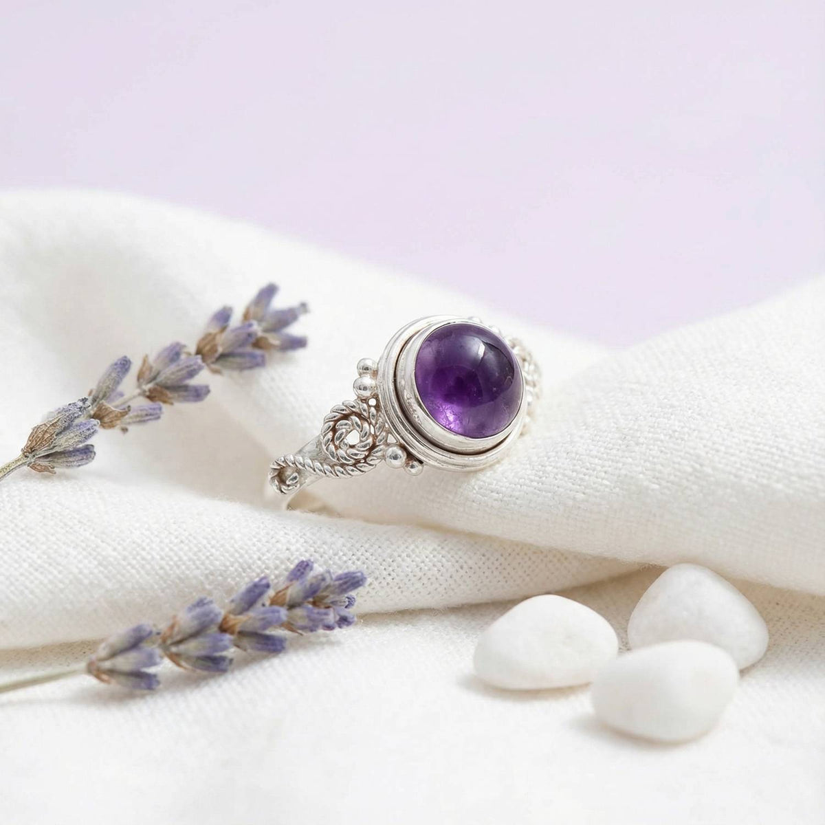 Silberring mit Amethyst auf hellem Stoff