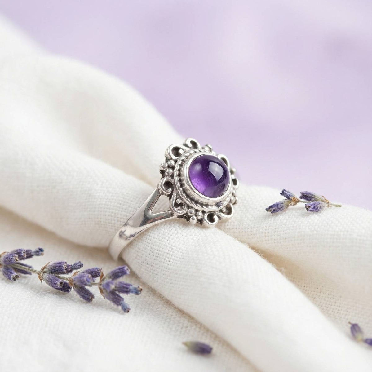 Silberring mit Amethyst auf hellem Stoff