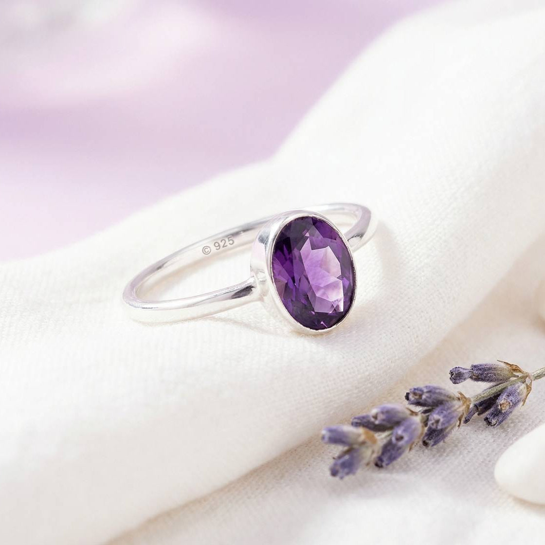 Silberring mit Amethyst auf hellem Stoff