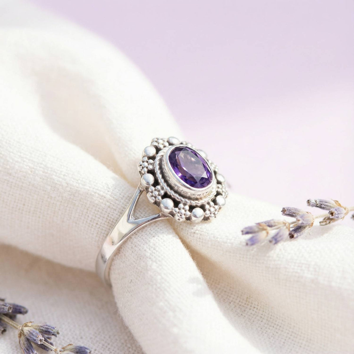 Silberring mit Amethyst auf hellem Stoff