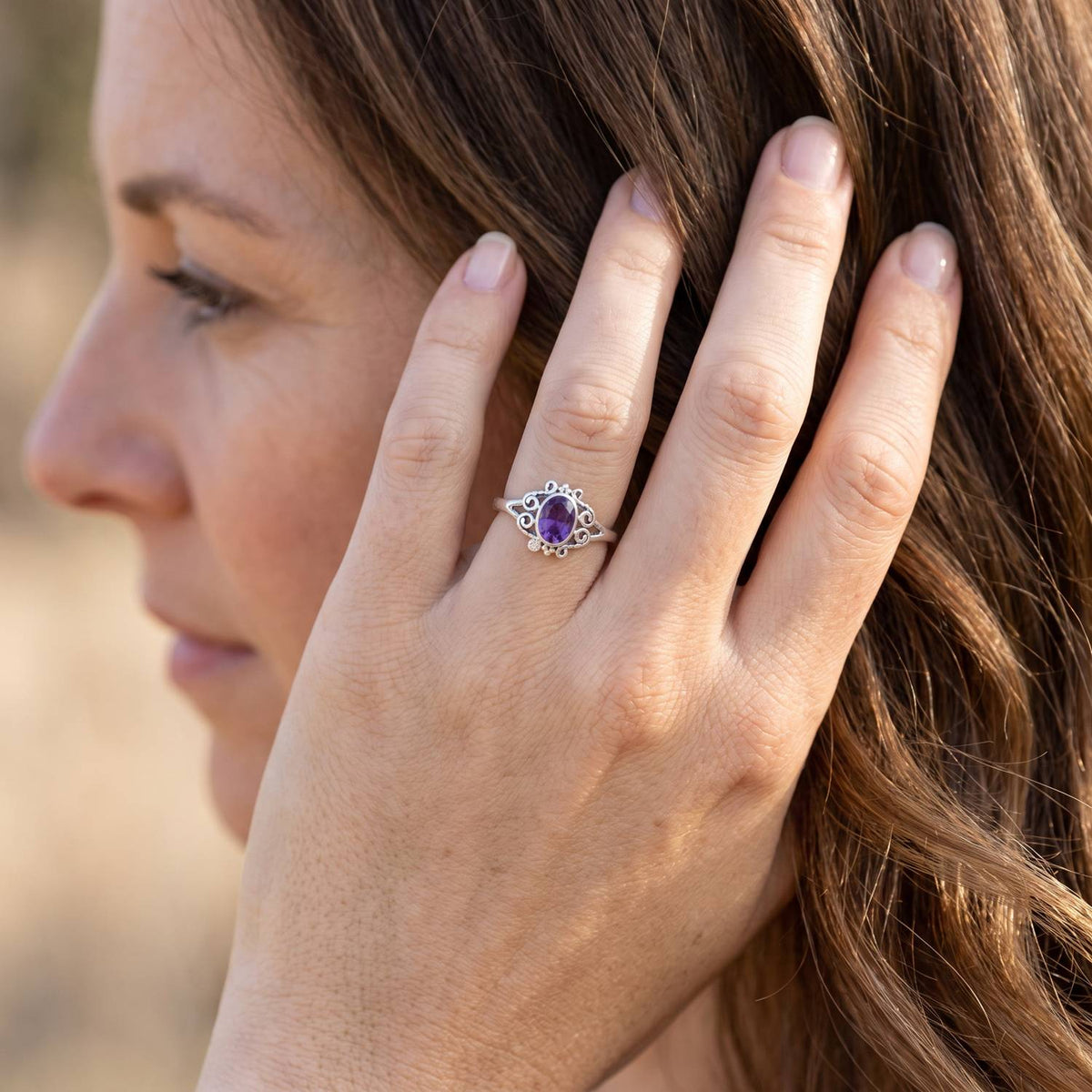 Frau trägt Silberring mit Amethyst an der Hand am Haar