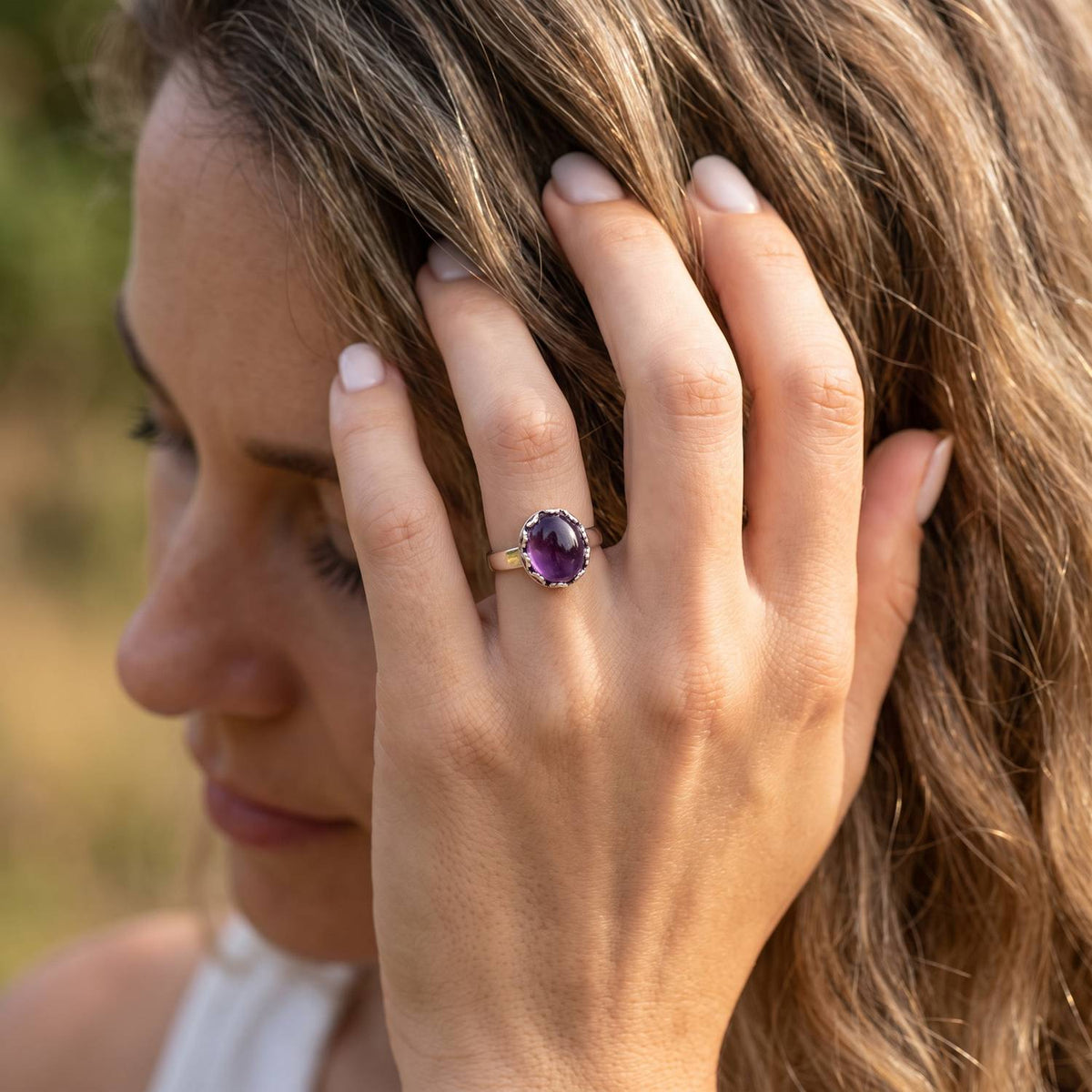 Frau trägt Silberring mit Amethyst an der Hand am Haar