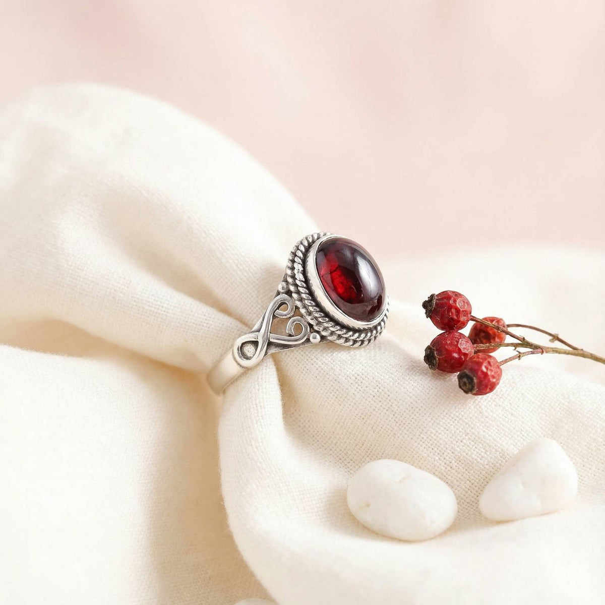 Silberring mit Granat auf hellem Stoff