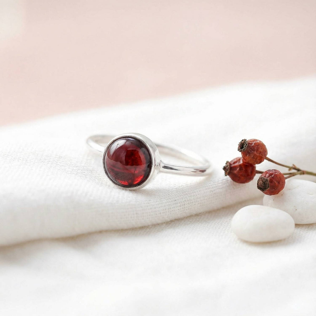 Silberring mit Granat auf hellem Stoff