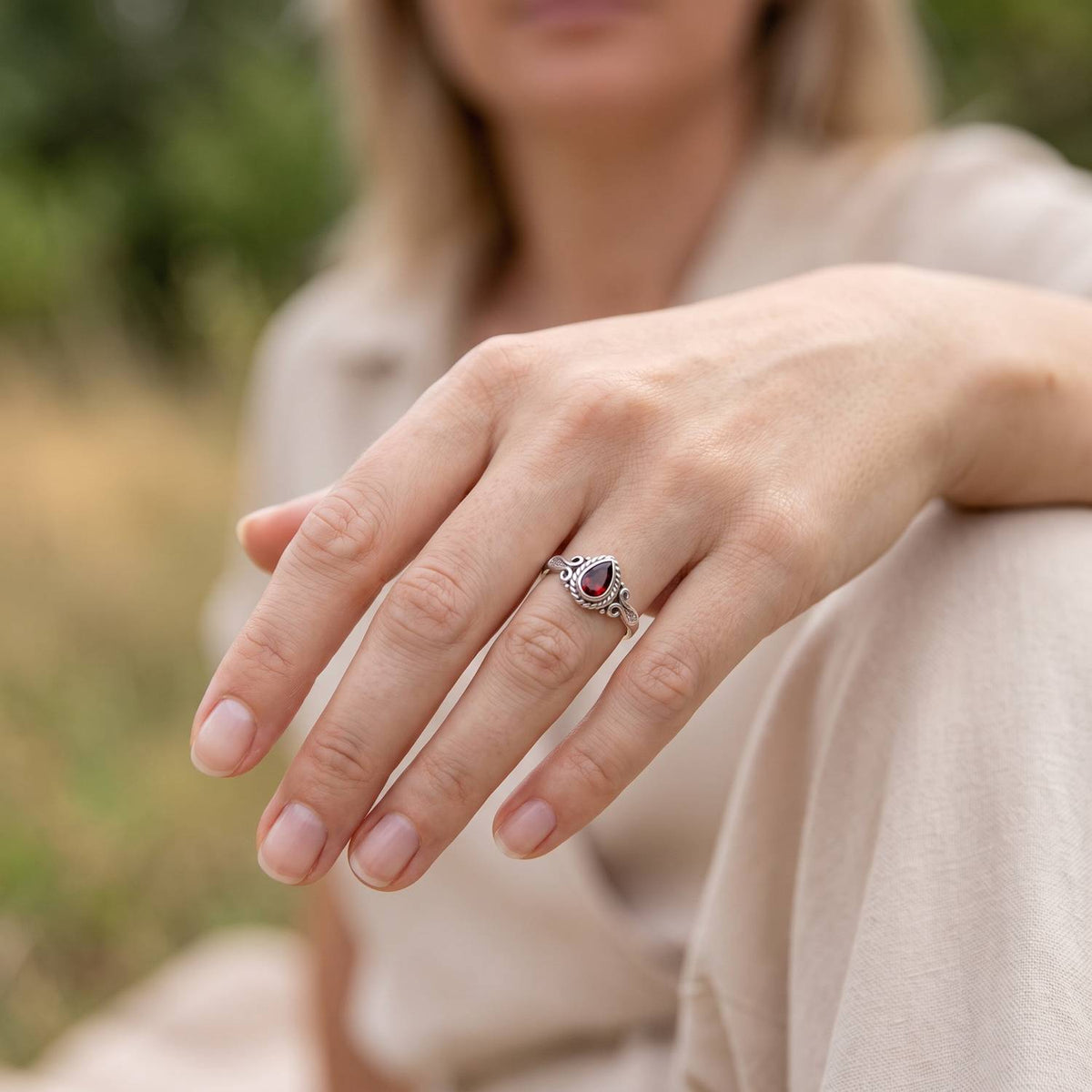 Granatring aus Silber getragen an der Hand im Freien
