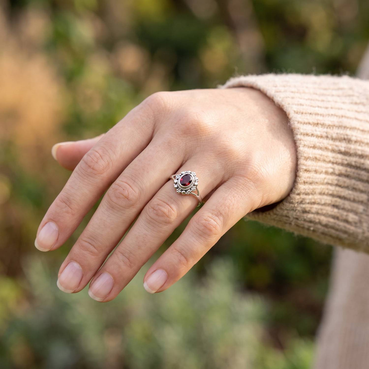 Granatring aus Silber getragen an der Hand im Freien