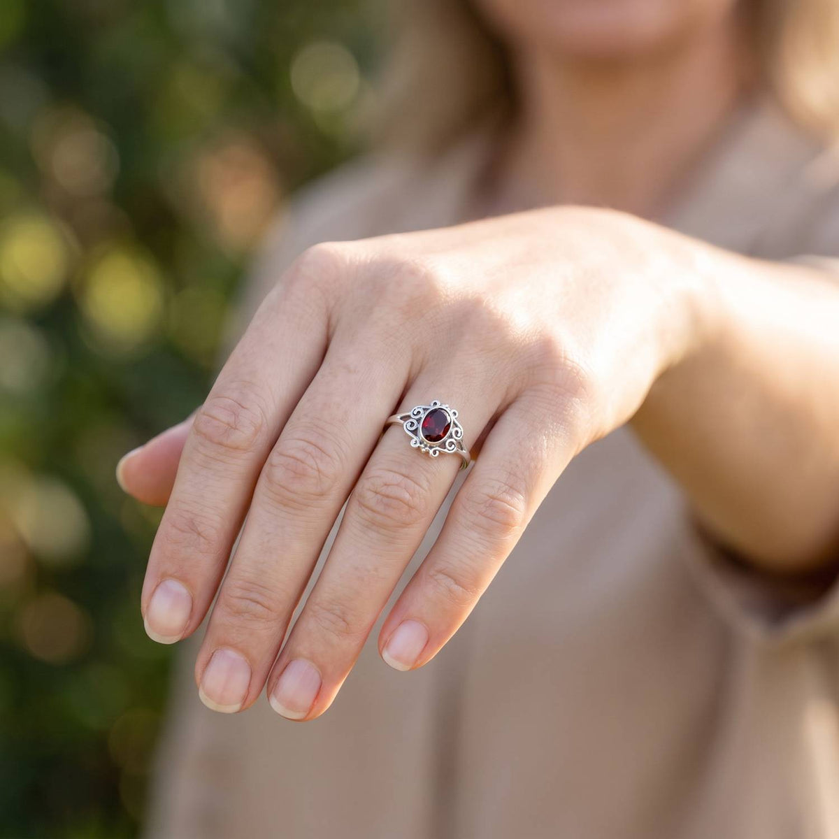 Granatring aus Silber getragen an der Hand im Freien
