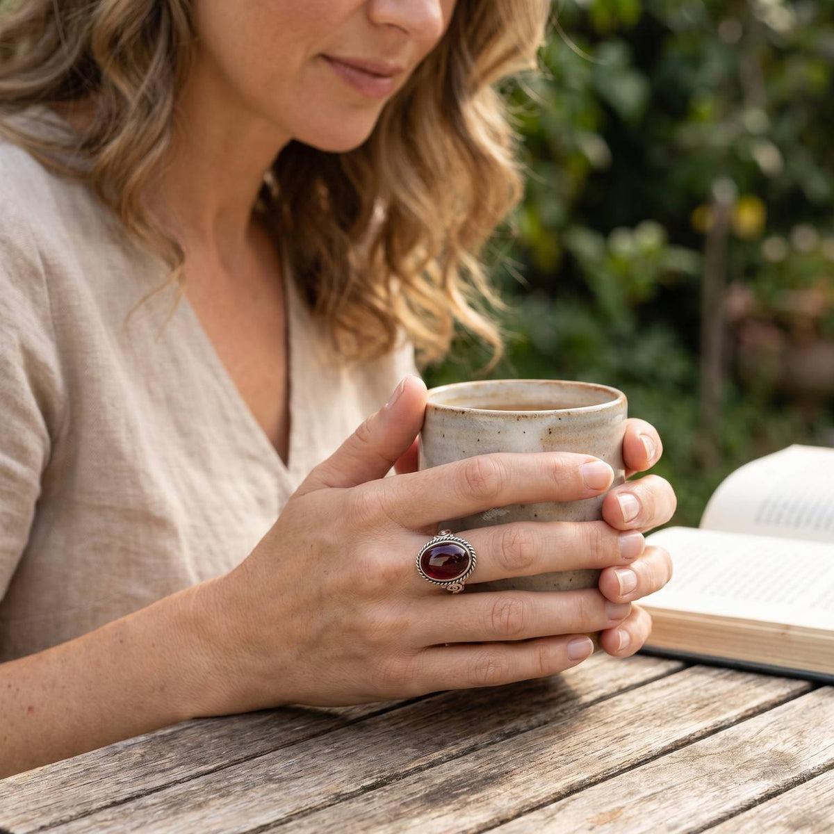 Granatring aus Silber getragen beim Lesen mit einer Tasse