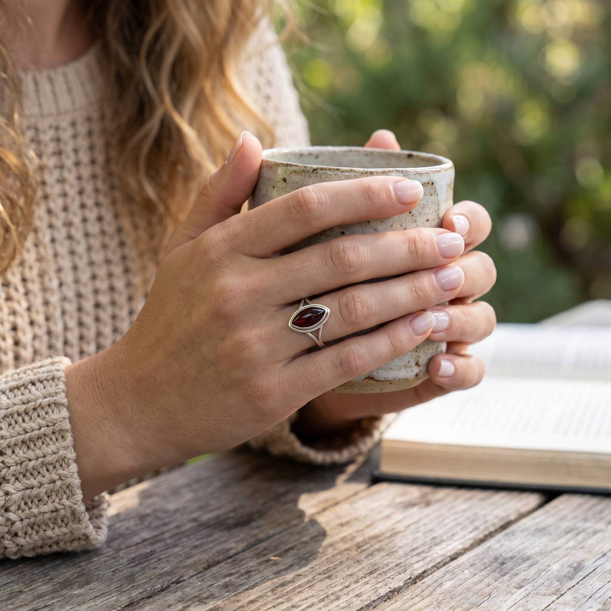Granatring aus Silber getragen beim Lesen mit einer Tasse