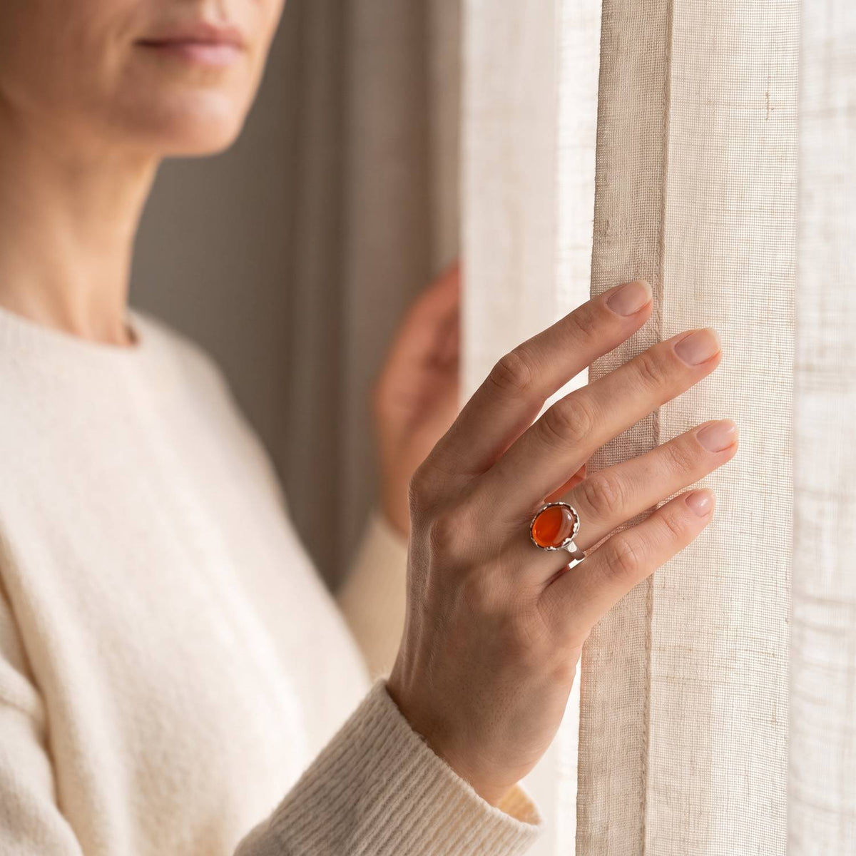 Frau trägt einen Karneolring aus Silber am Fenster