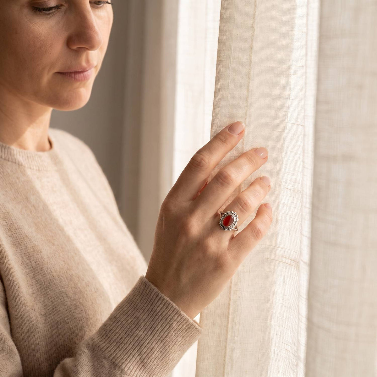 Frau trägt einen Karneolring aus Silber am Fenster