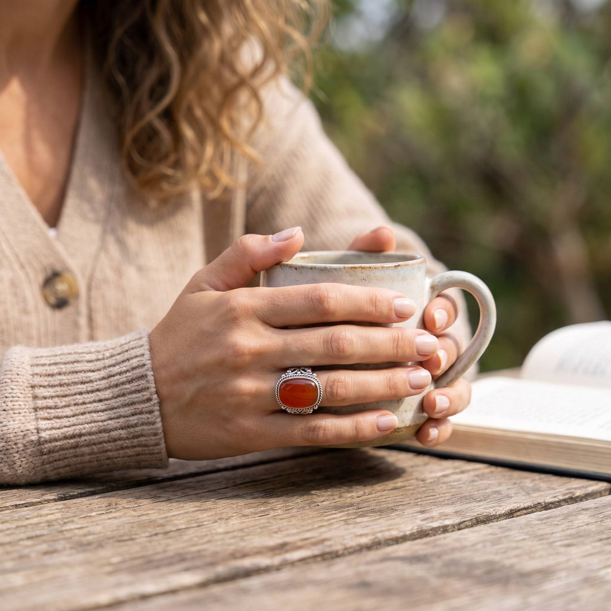 Karneolring aus Silber getragen beim Lesen mit einer Tasse