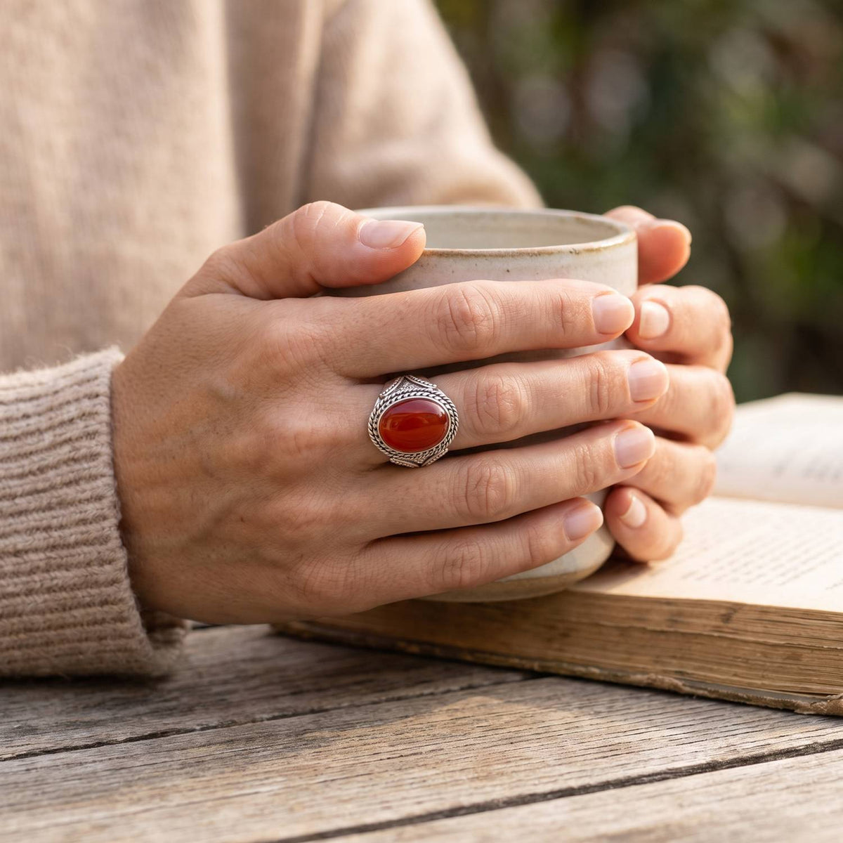 Karneolring aus Silber getragen beim Lesen mit einer Tasse