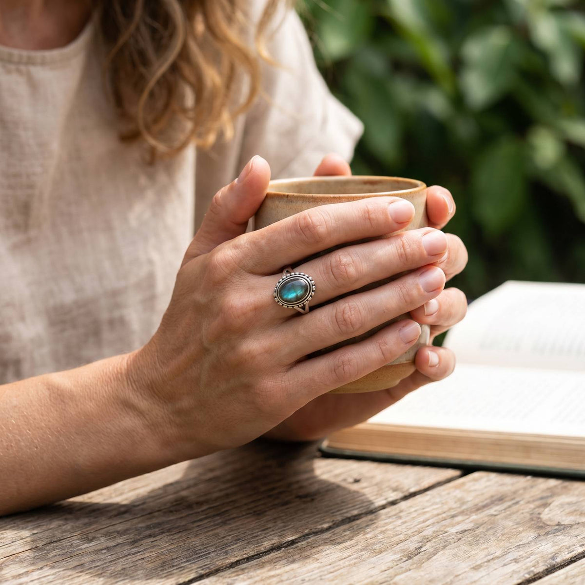 Labradoritring aus Silber getragen beim Lesen mit einer Tasse