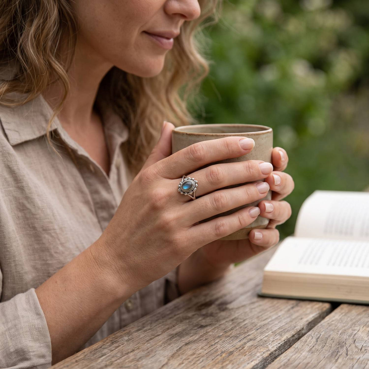 Labradoritring aus Silber getragen beim Lesen mit einer Tasse