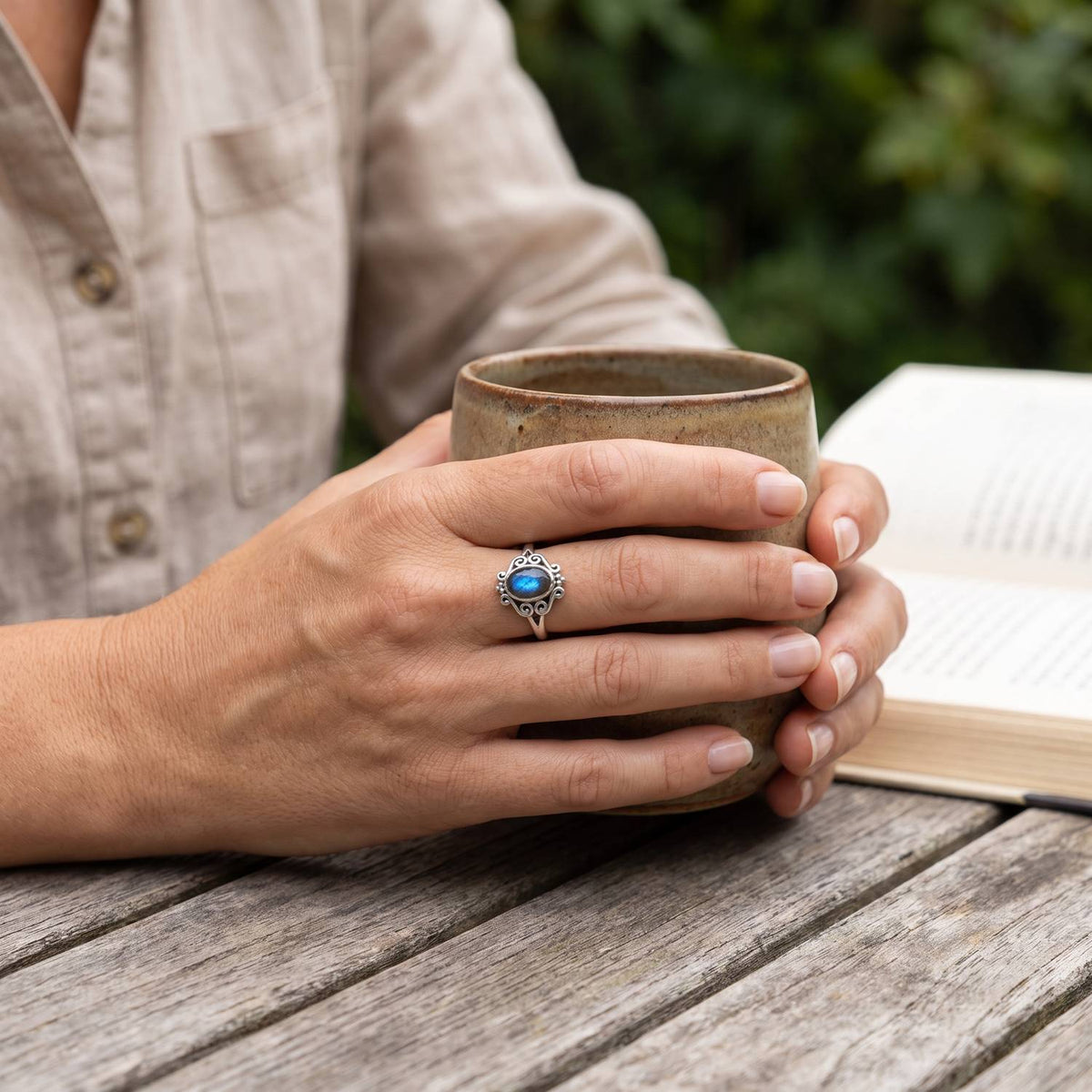 Labradoritring aus Silber getragen beim Lesen mit einer Tasse