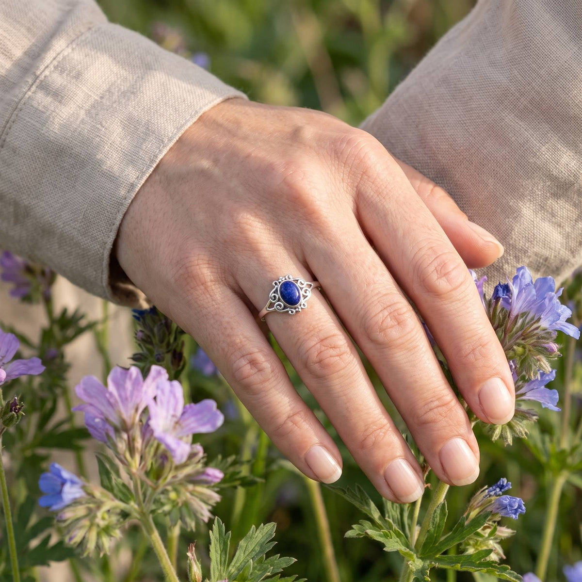 Silberring mit Lapislazuli an der Hand zwischen Blumen