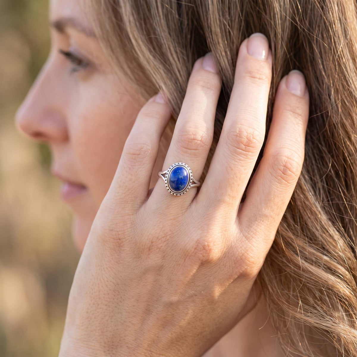 Frau trägt Silberring mit Lapislazuli an der Hand am Haar