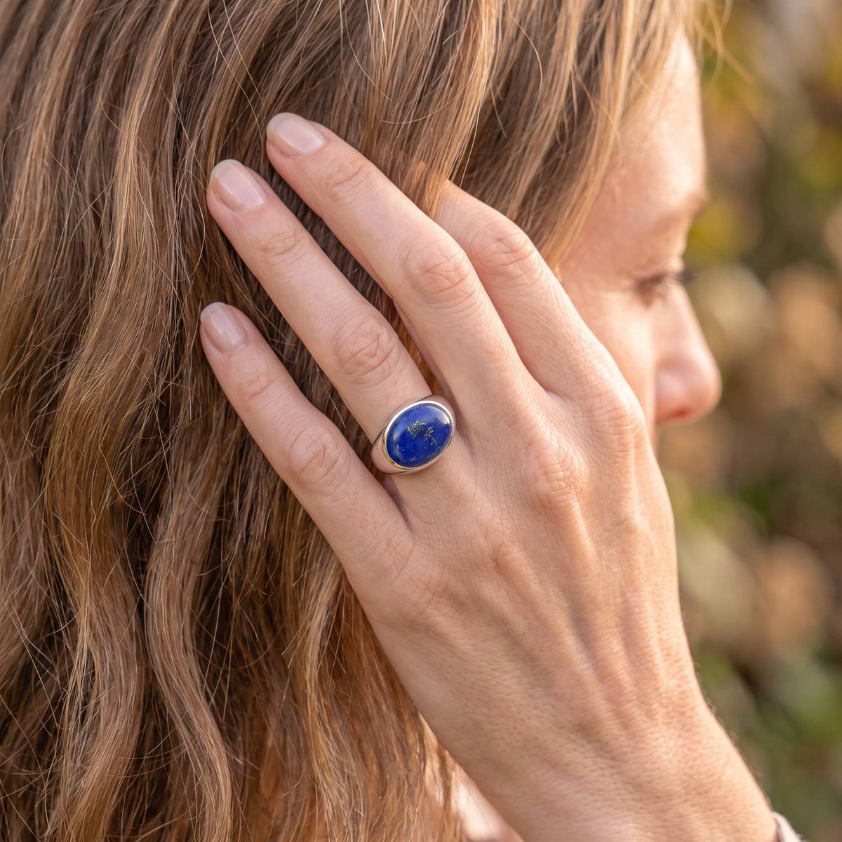 Frau trägt Silberring mit Lapislazuli an der Hand am Haar