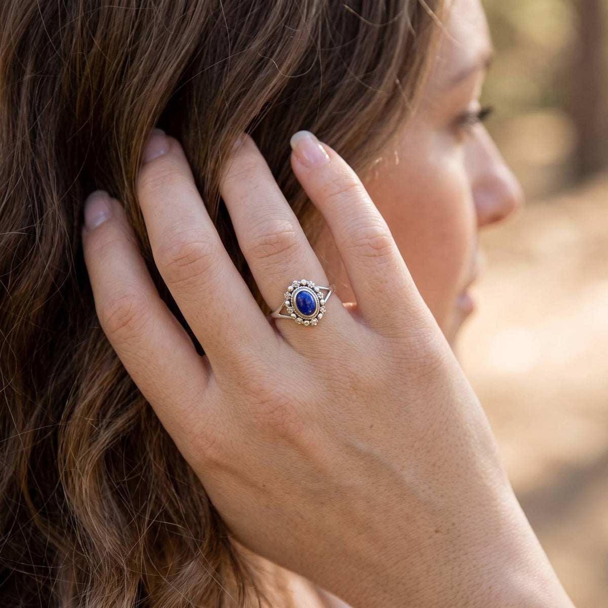 Frau trägt Silberring mit Lapislazuli an der Hand am Haar