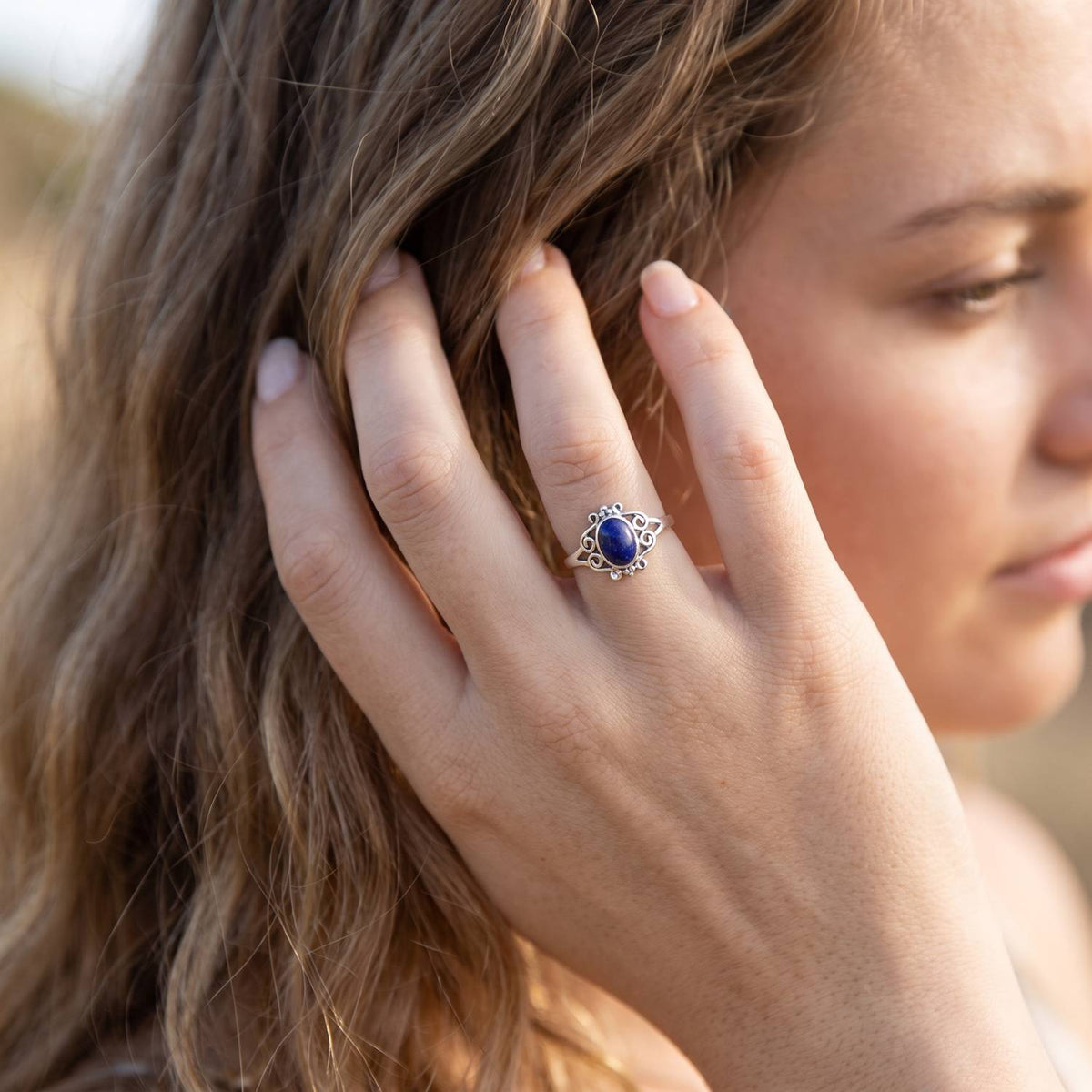 Frau trägt Silberring mit Lapislazuli an der Hand am Haar