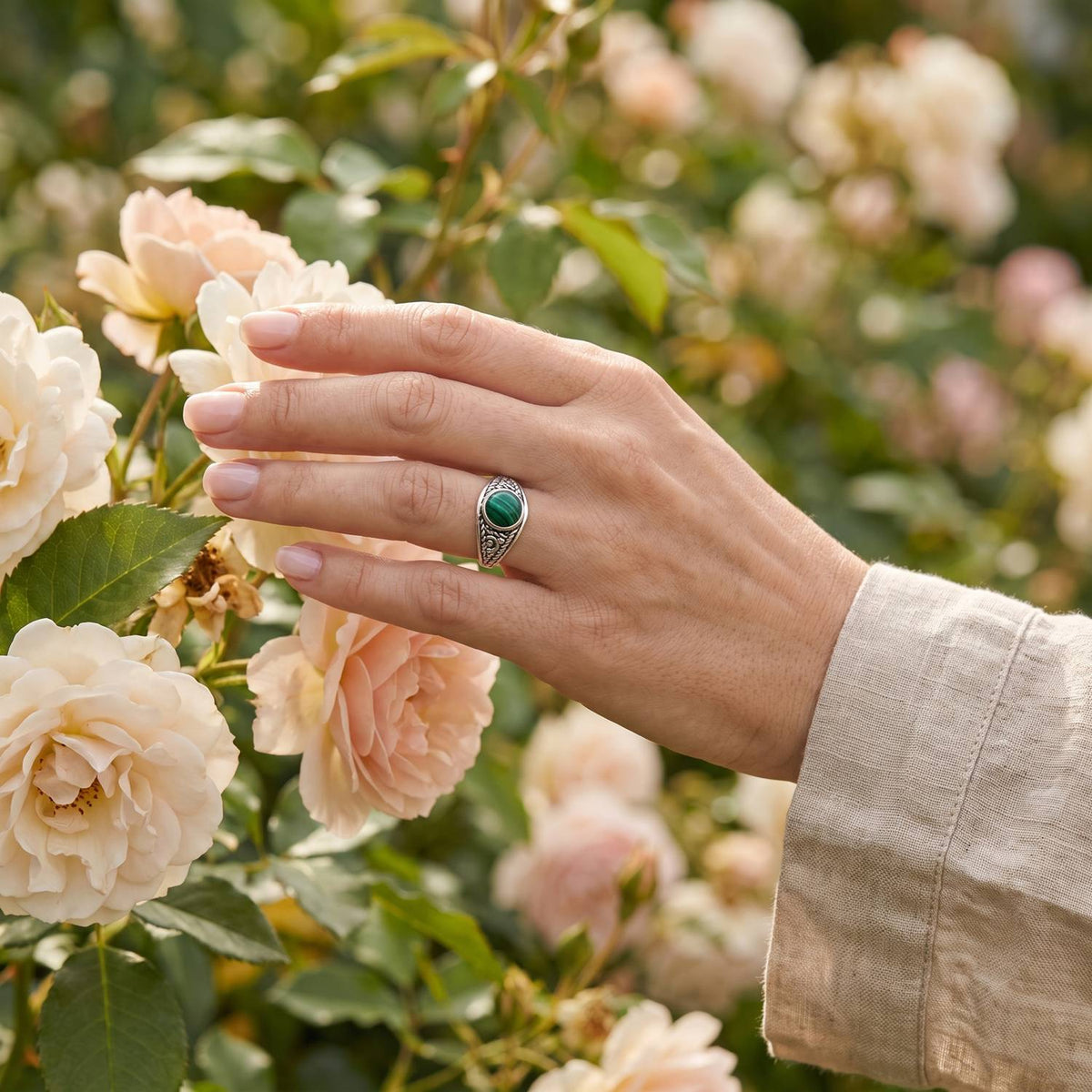 Silberring mit Malachit an der Hand zwischen Blumen