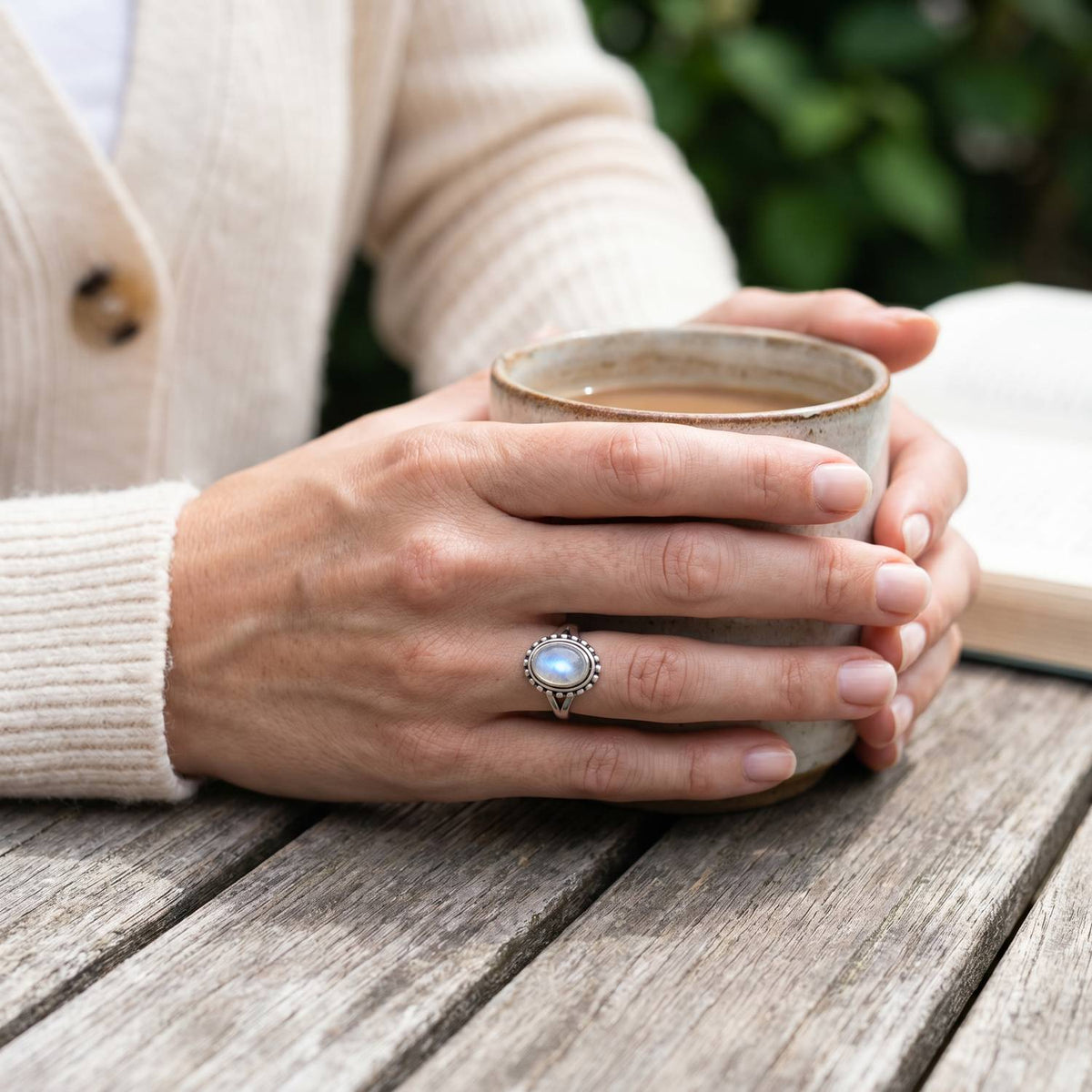 Mondsteinring aus Silber getragen beim Lesen mit einer Tasse