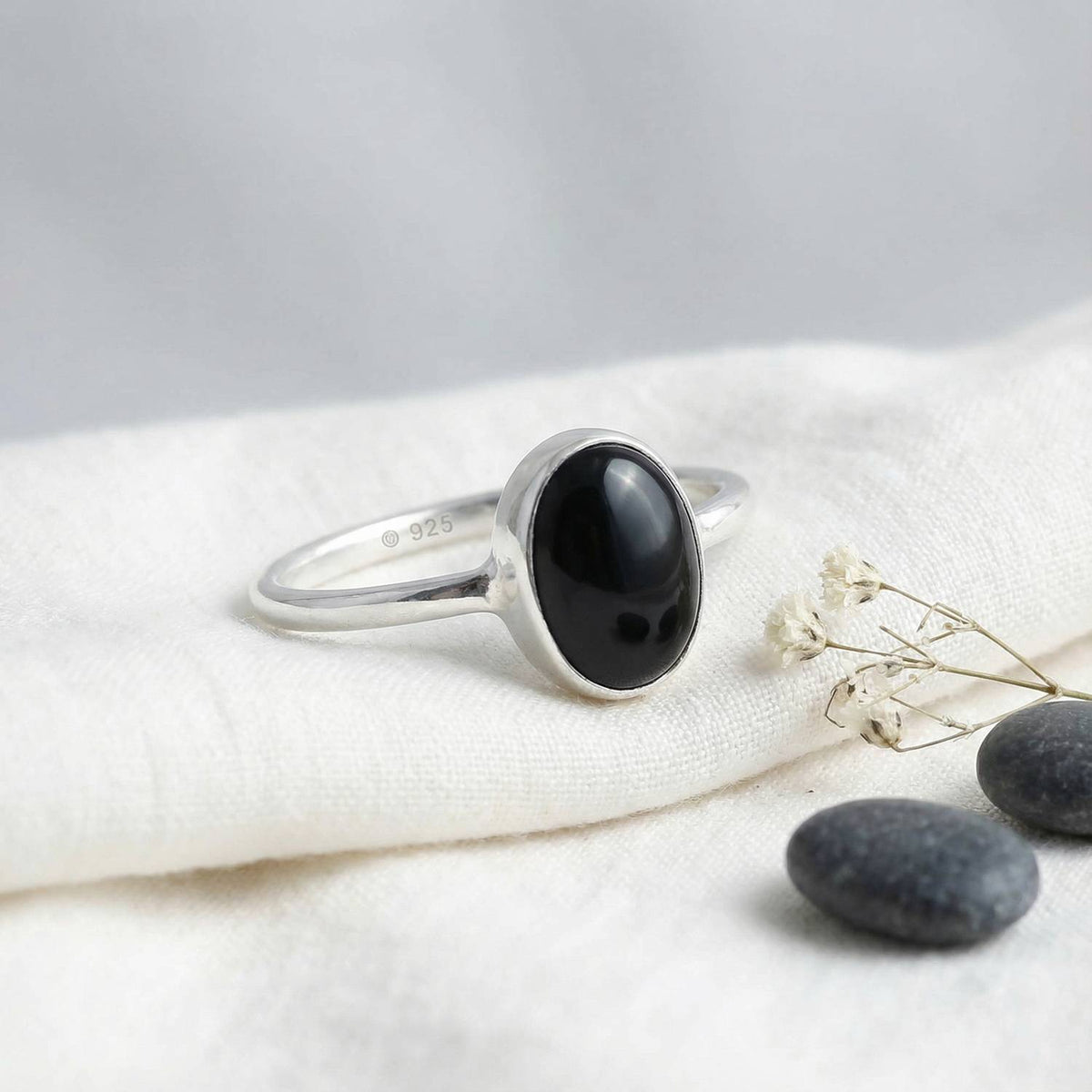 Silberring mit Onyx auf hellem Stoff