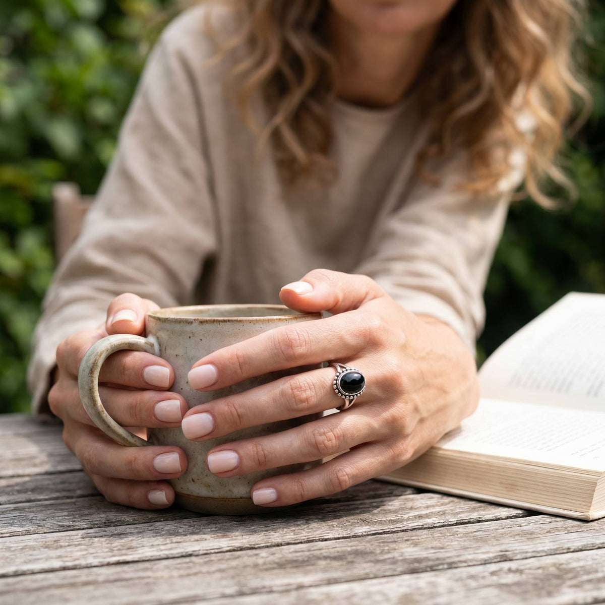 Onyxring aus Silber getragen beim Lesen mit einer Tasse