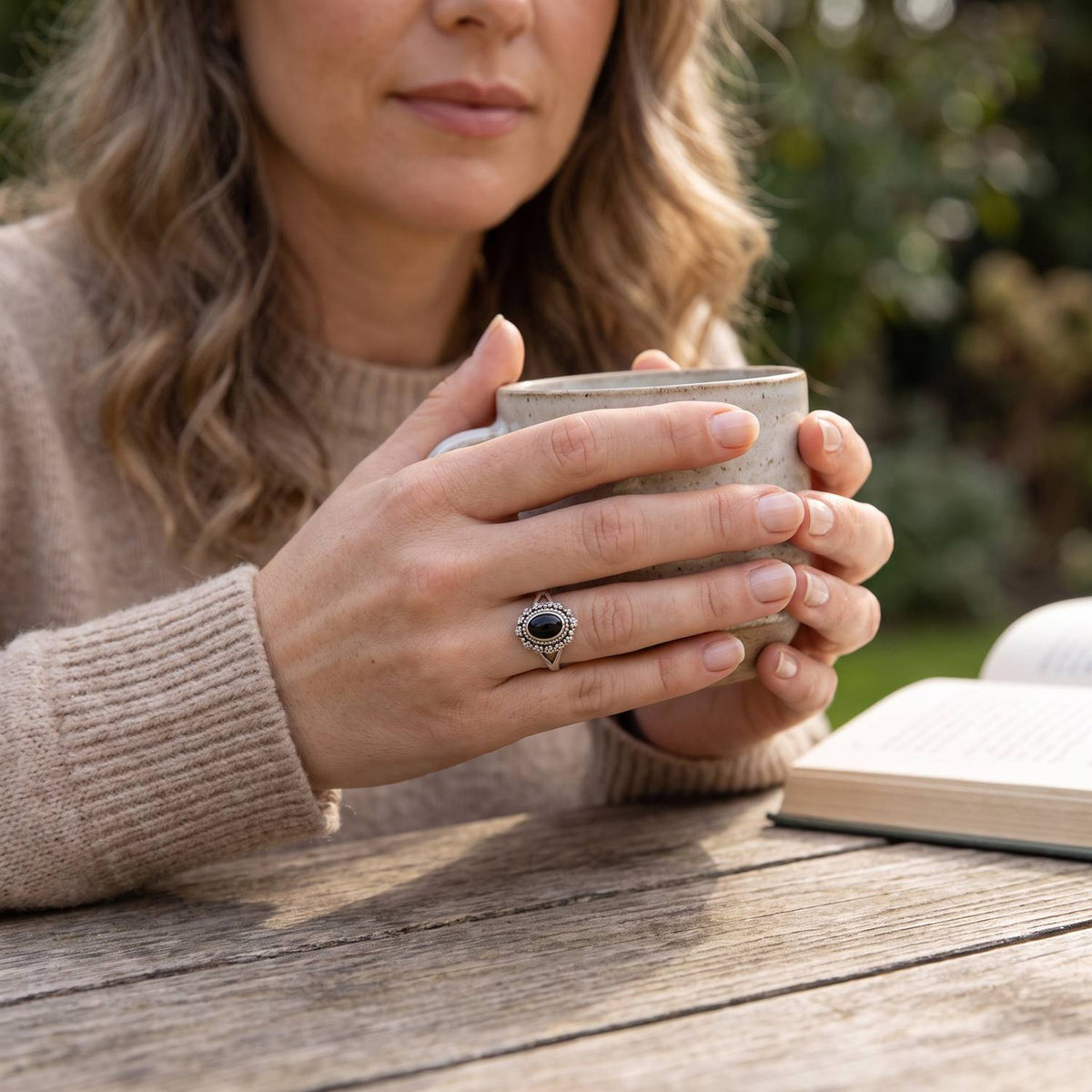 Onyxring aus Silber getragen beim Lesen mit einer Tasse