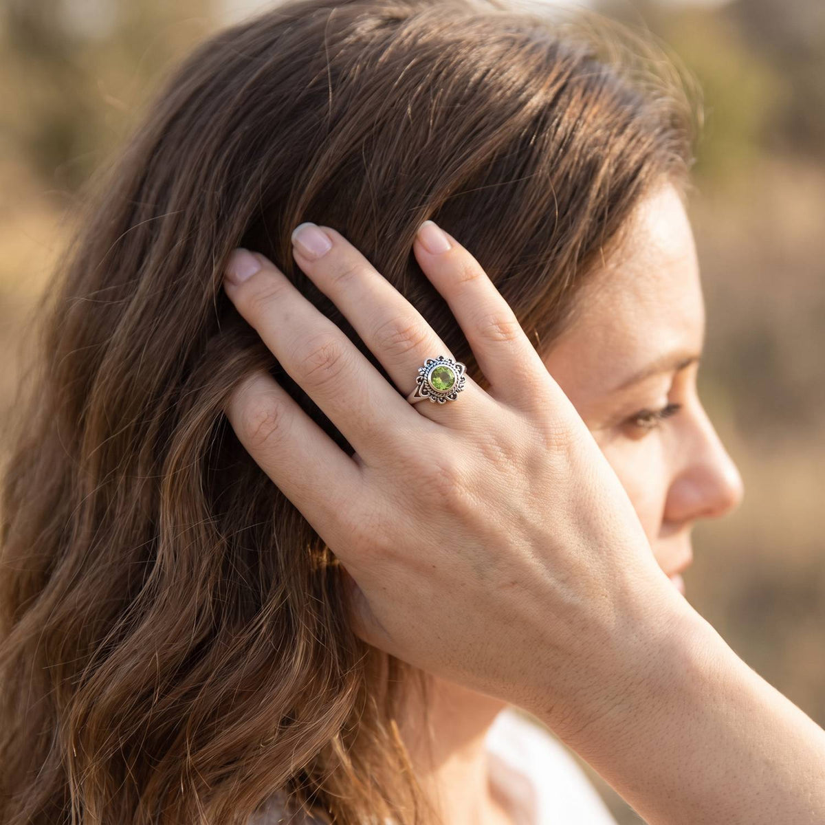 Frau trägt Silberring mit Peridot an der Hand am Haar