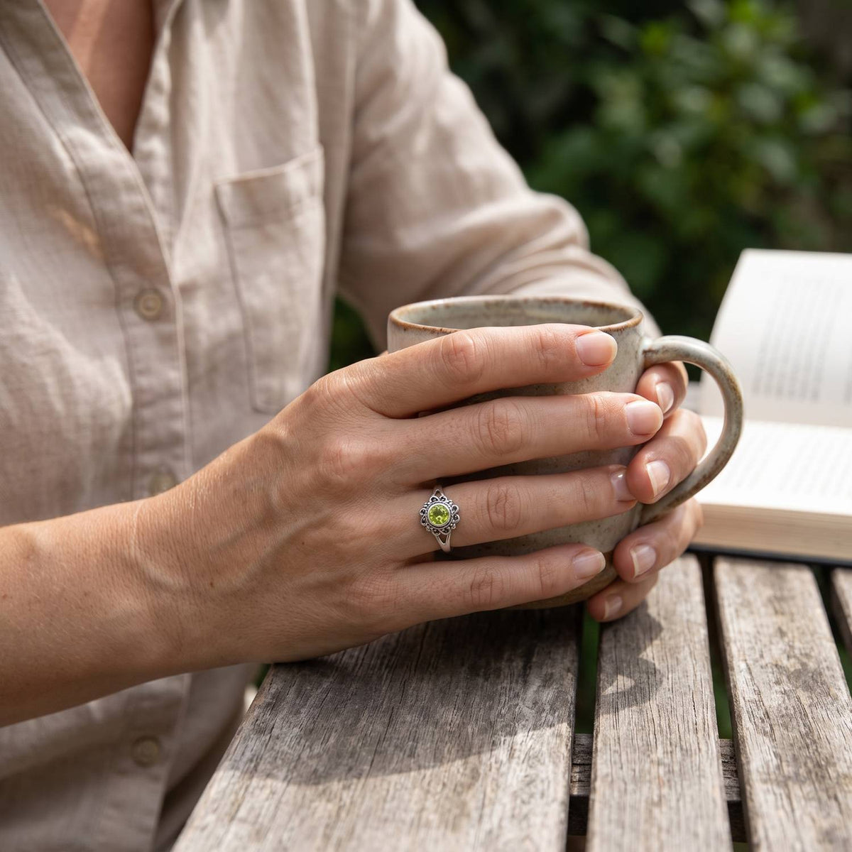 Peridotring aus Silber getragen beim Lesen mit einer Tasse