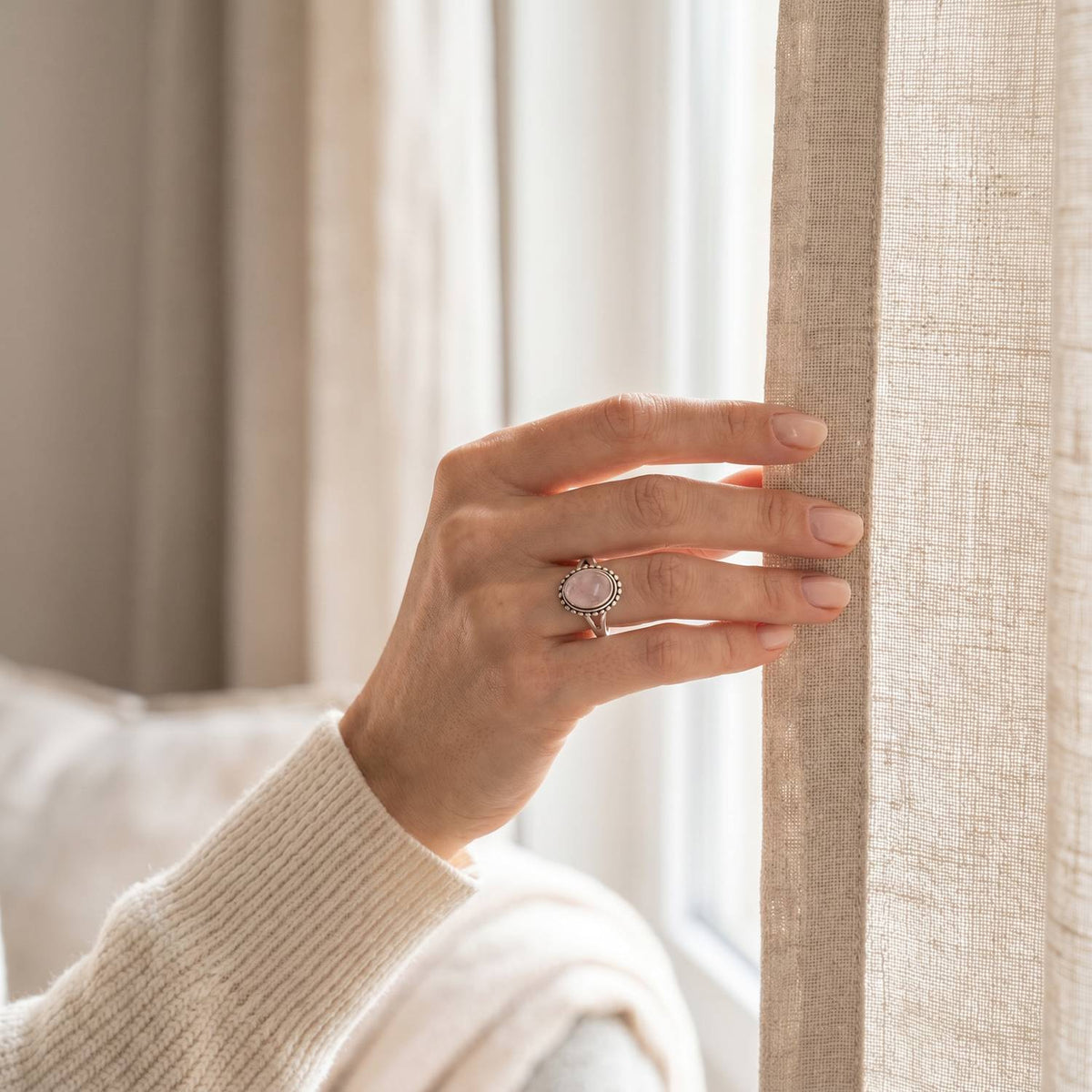 Frau trägt einen Rosenquarzring aus Silber am Fenster