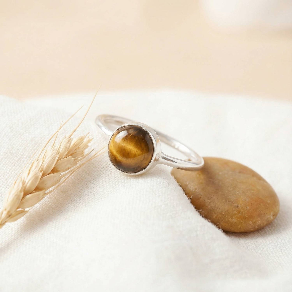 Silberring mit Tigerauge auf hellem Stoff