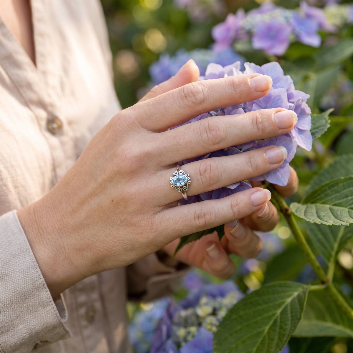 Silberring mit Topas an der Hand zwischen Blumen