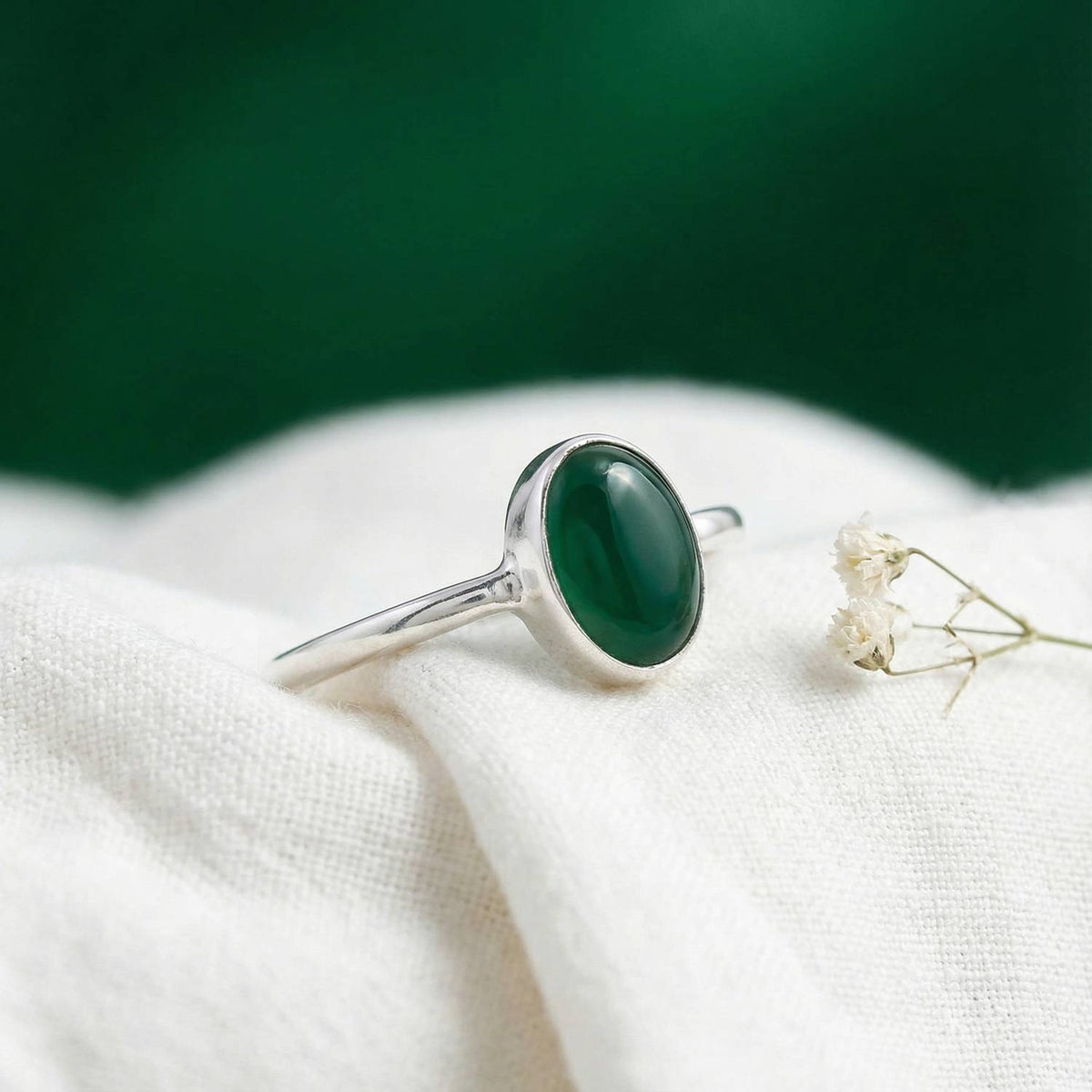 Silberring mit grüner Onyx auf hellem Stoff