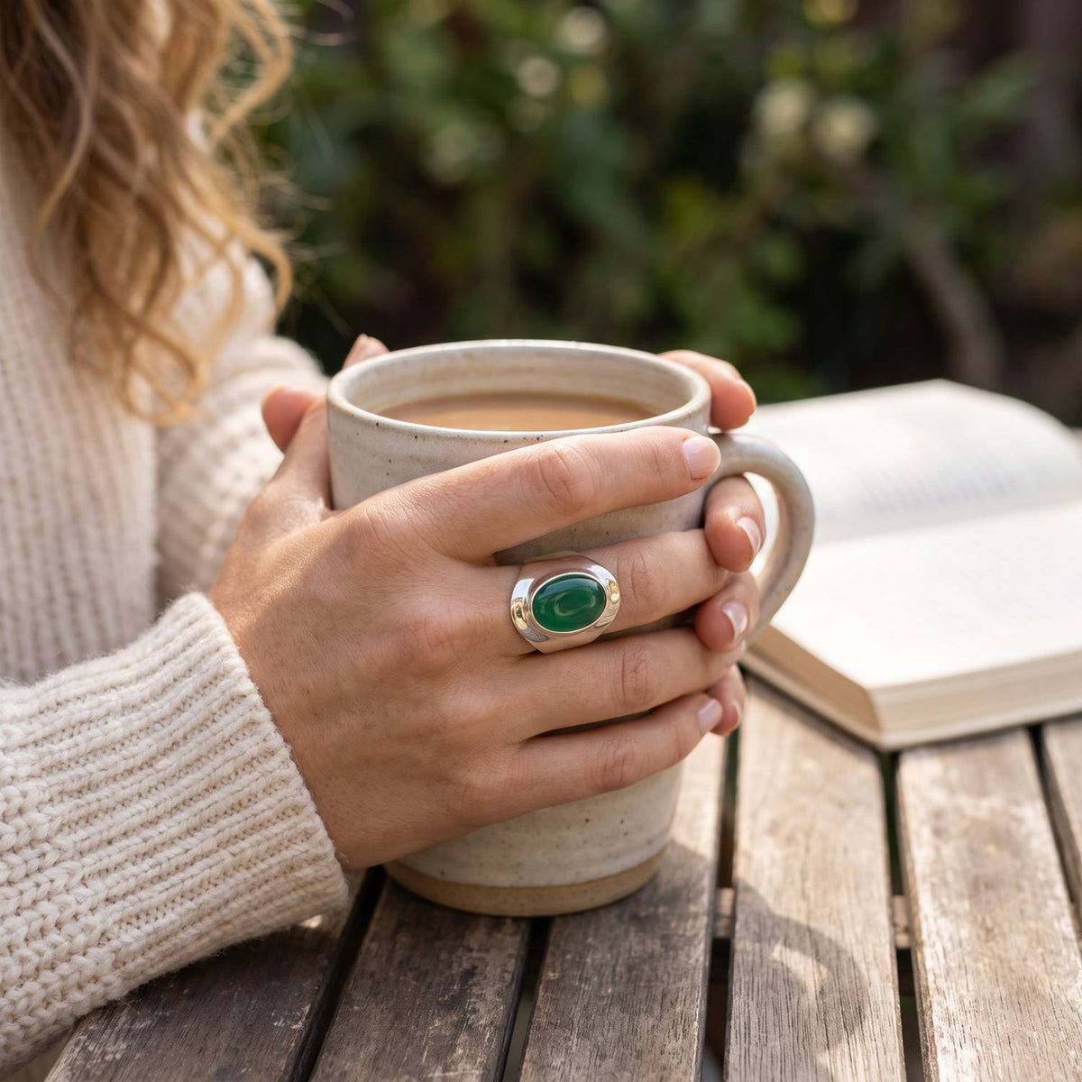 grüner Onyxring aus Silber getragen beim Lesen mit einer Tasse