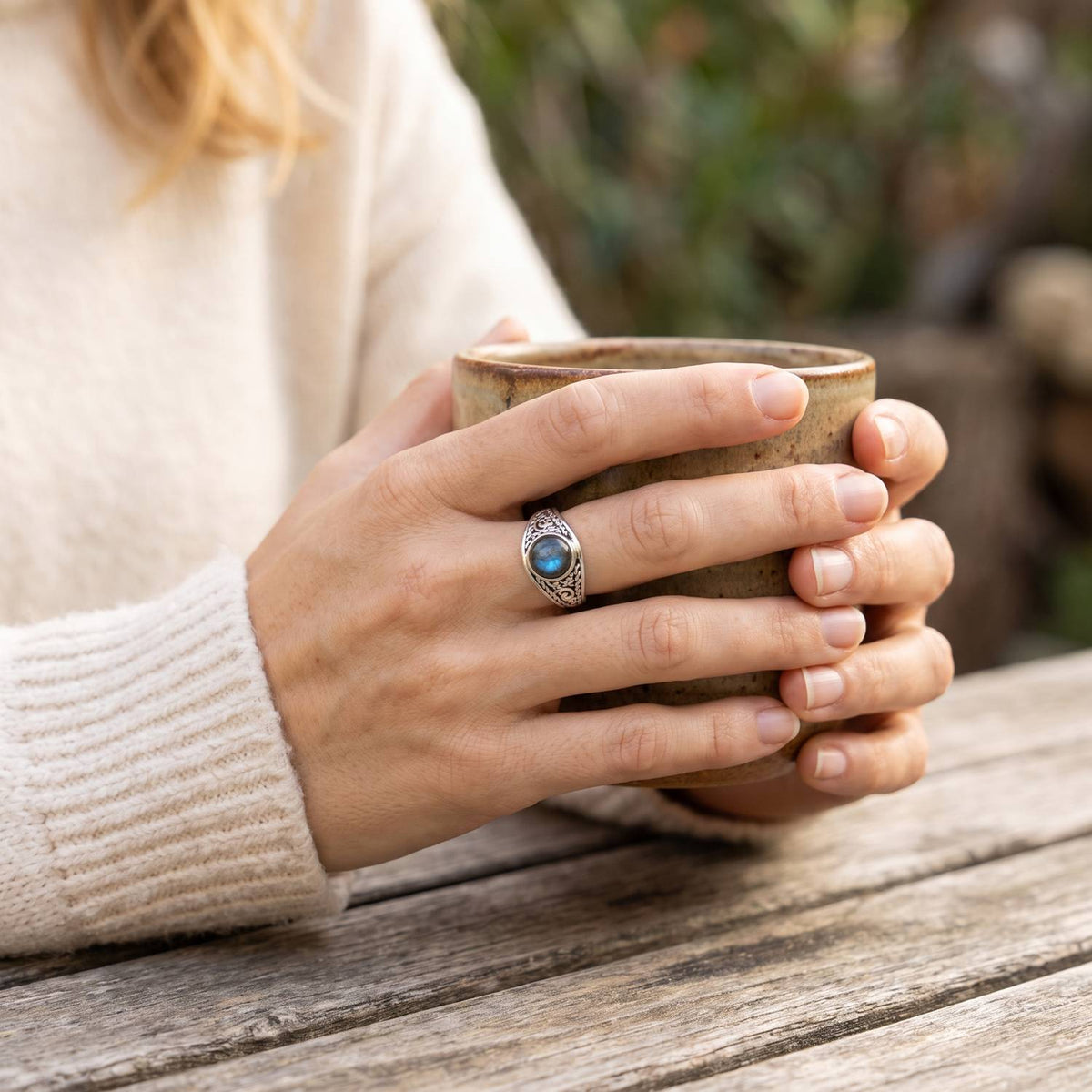 Labradoritring aus Silber getragen beim Lesen mit einer Tasse