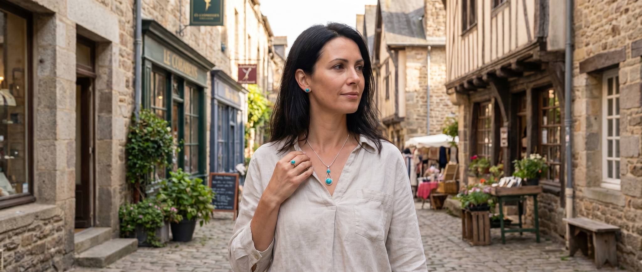 Frau mit türkisfarbenem Silberschmuck zu einer hellen Leinenbluse in einer historischen Altstadt