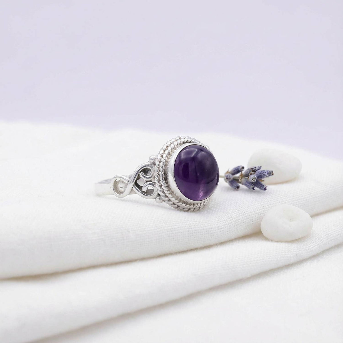 Silberring mit Amethyst auf hellem Stoff