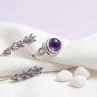 [KI] Silberring mit Amethyst auf hellem Stoff