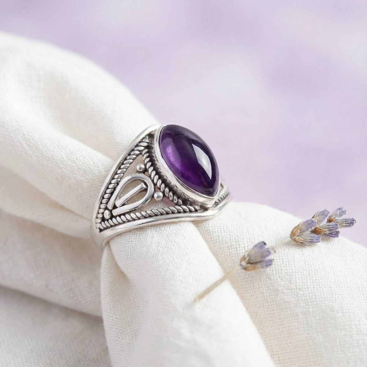 Silberring mit Amethyst auf hellem Stoff