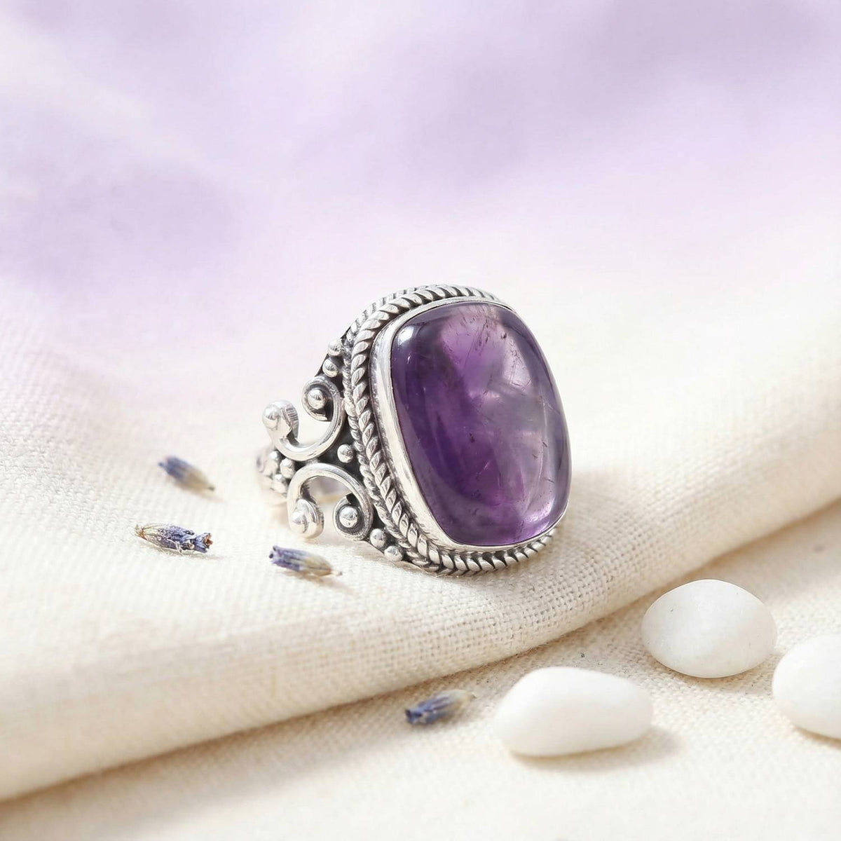 Silberring mit Amethyst auf hellem Stoff