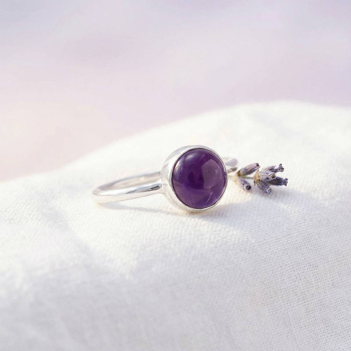 Silberring mit Amethyst auf hellem Stoff