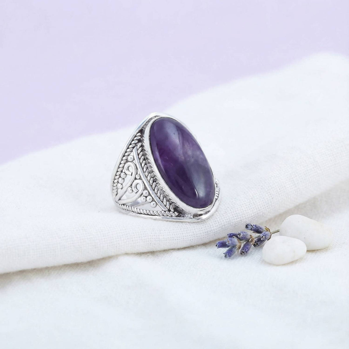 Silberring mit Amethyst auf hellem Stoff
