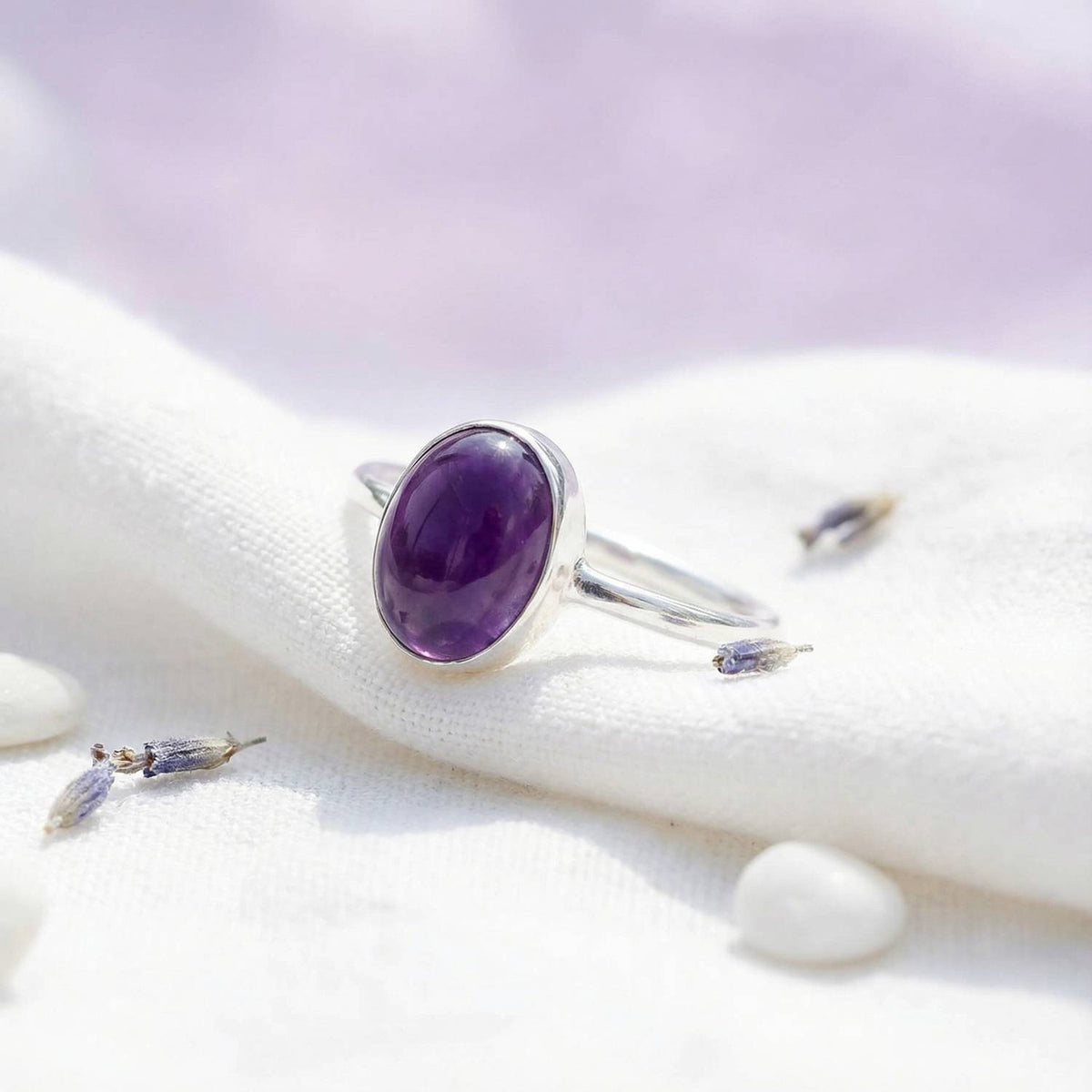 Silberring mit Amethyst auf hellem Stoff