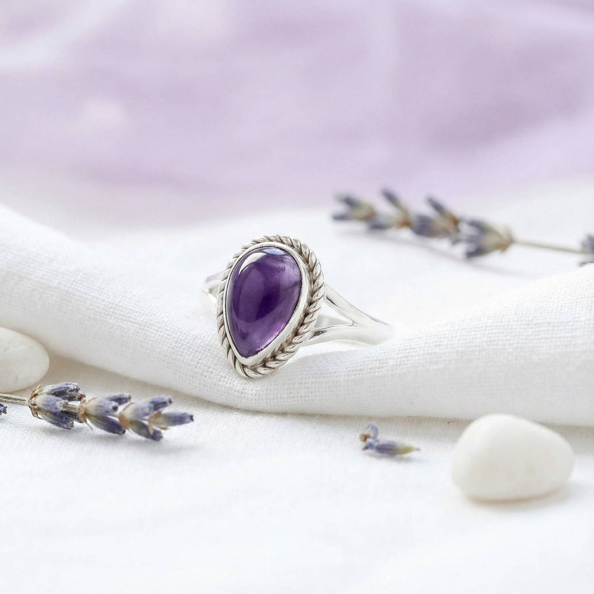 Silberring mit Amethyst auf hellem Stoff