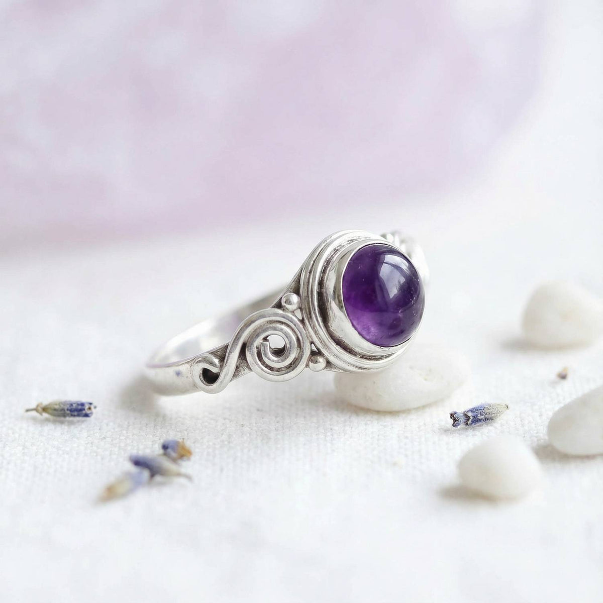 Silberring mit Amethyst auf hellem Stoff