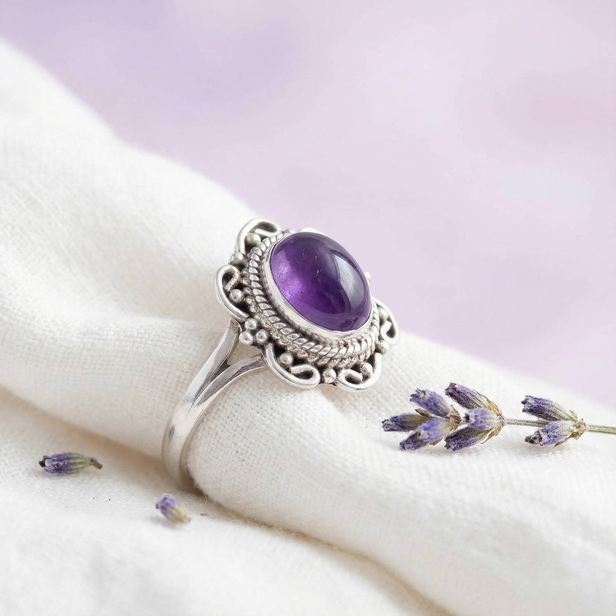 Silberring mit Amethyst auf hellem Stoff